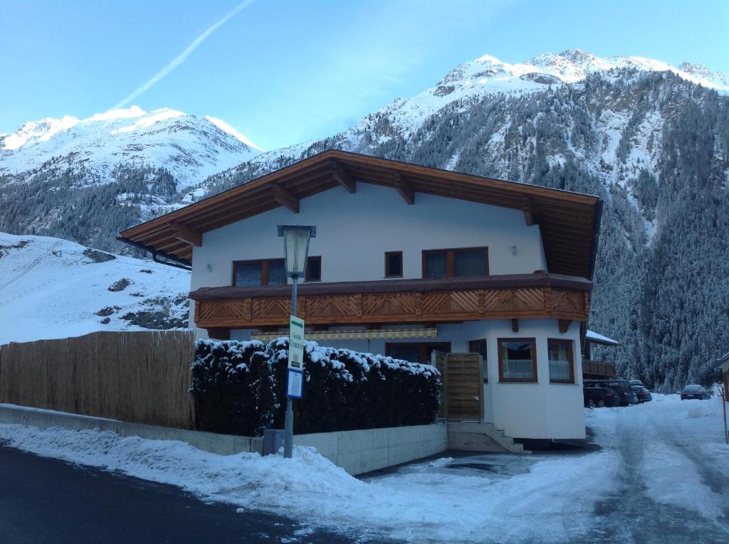 uma casa na neve com montanhas ao fundo em Appartement Gisela em Sölden