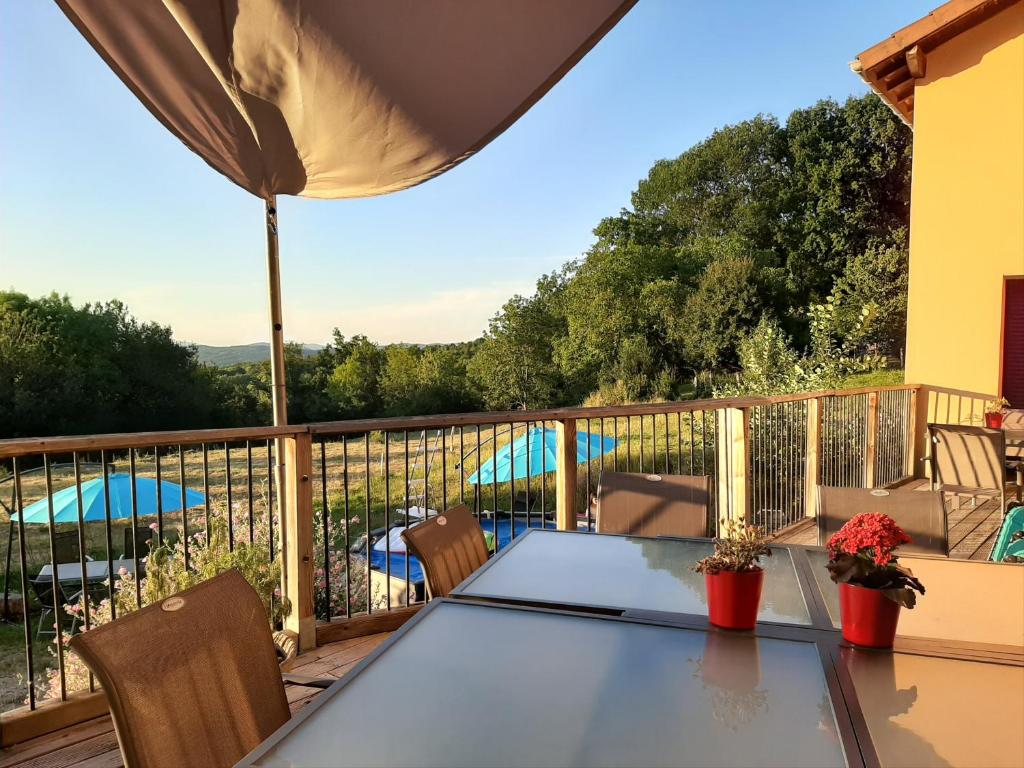 einen Balkon mit einem Tisch und Stühlen auf einer Terrasse in der Unterkunft Le Grand Noyer in Ambronay