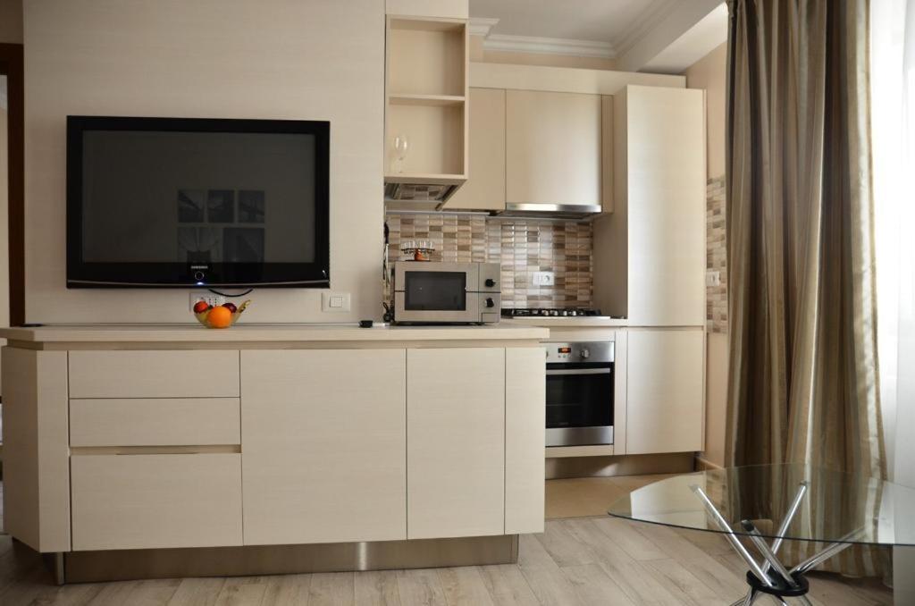 ママイアにあるSolid Residence Oanaの白いキャビネットと薄型テレビ付きのキッチンが備わります。