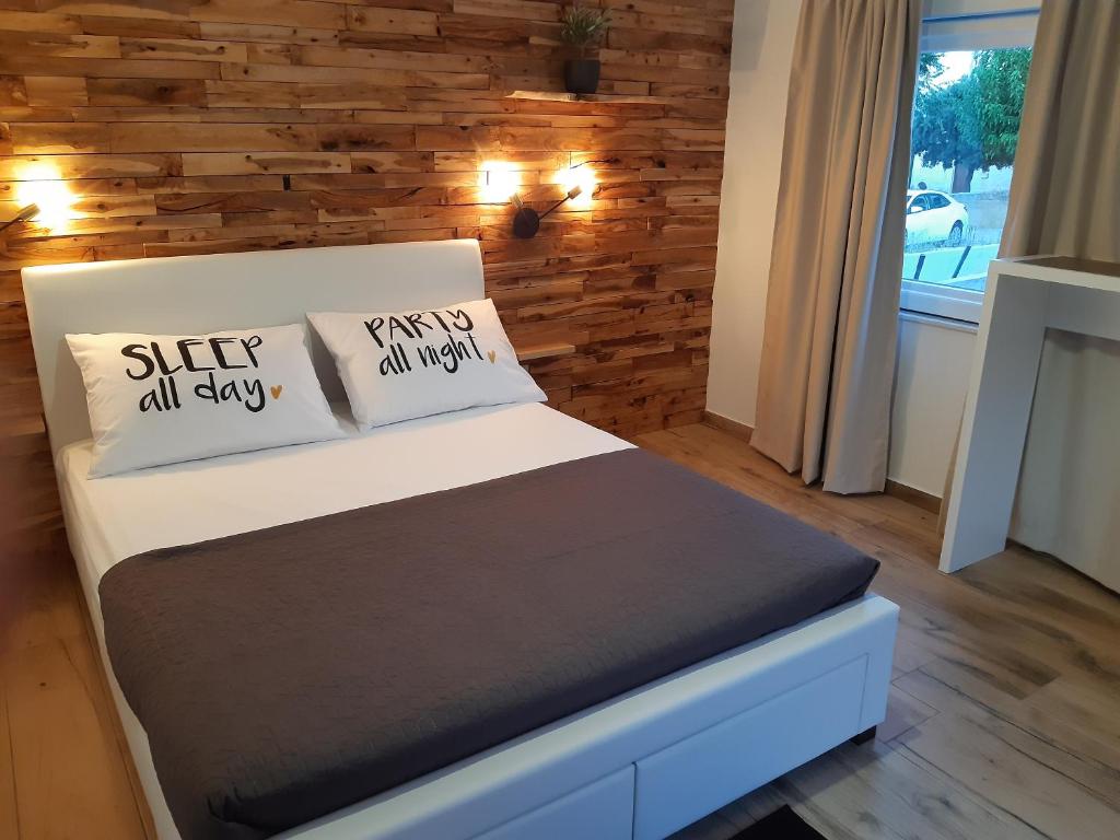 una camera da letto con letto, cuscini e parete in legno di little olive tree house a Sali (Sale)