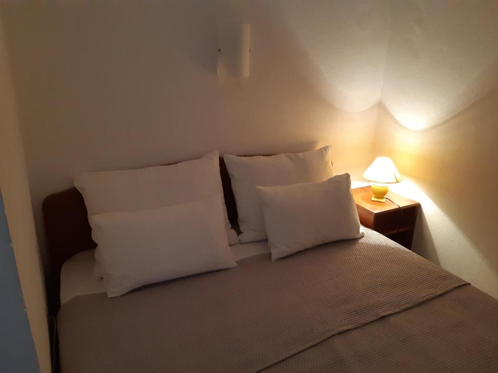 1 dormitorio con 1 cama con almohadas blancas y lámpara en Apartments Magdalena, en Pag