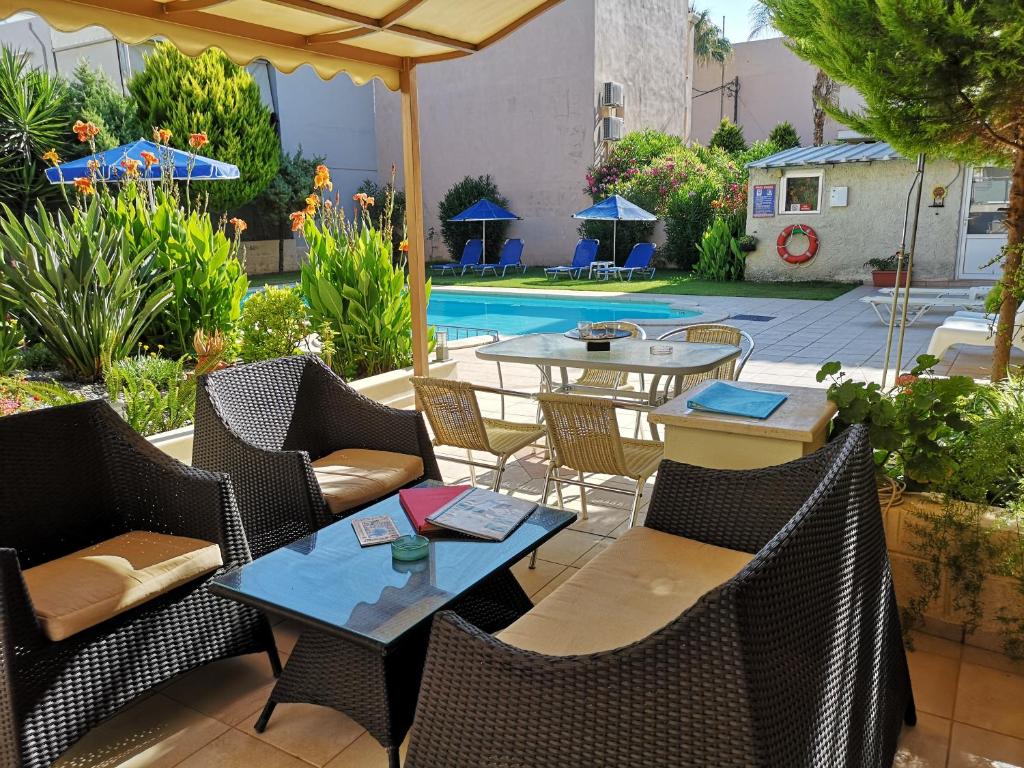 een patio met tafels en stoelen en een zwembad bij Nicolas Studios & Apartments in Agia Marina Nea Kydonias