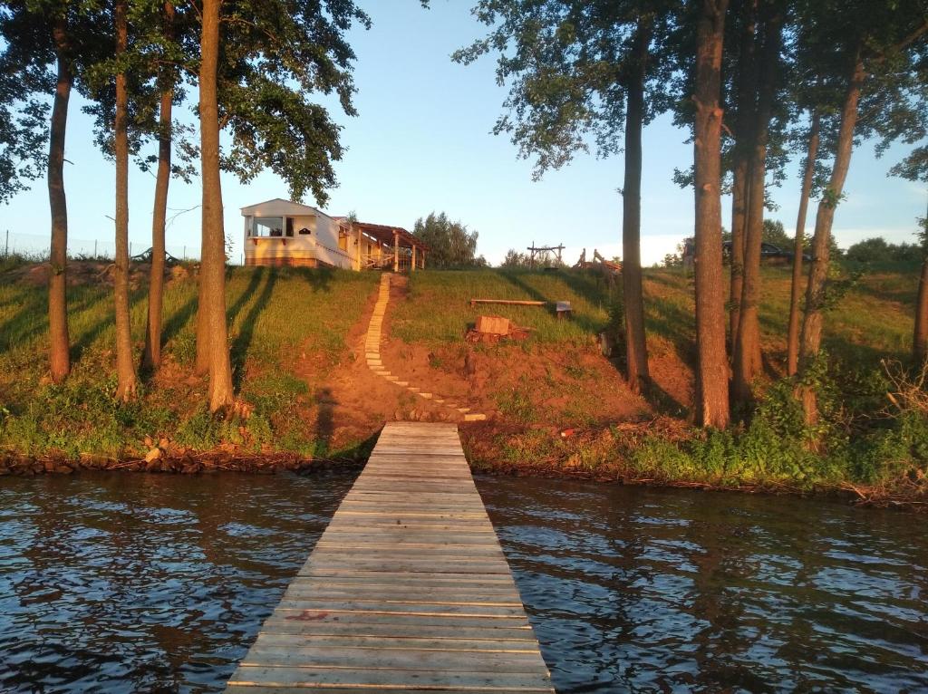 uma ponte de madeira sobre um rio com uma casa ao fundo em Domek letniskowy em Jeziorowskie