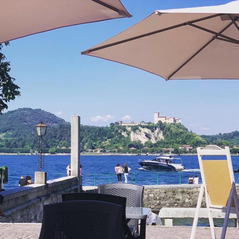 a table with an umbrella and a boat in the water at Il Giardino Segreto Arona, Charming Apartments in Arona