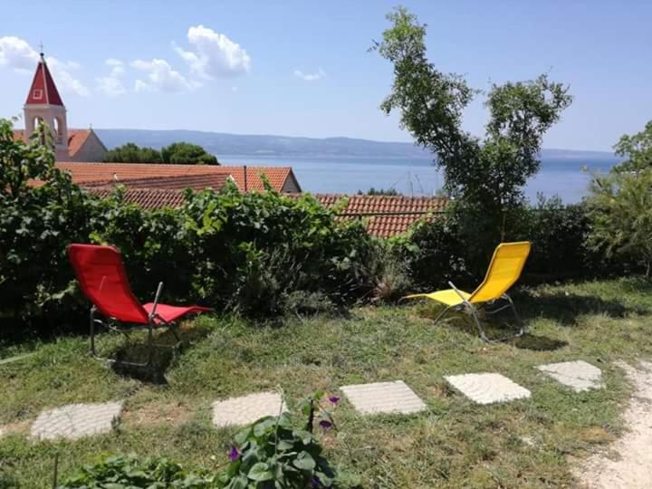 drie stoelen in het gras voor een huis bij Leonica in Omiš