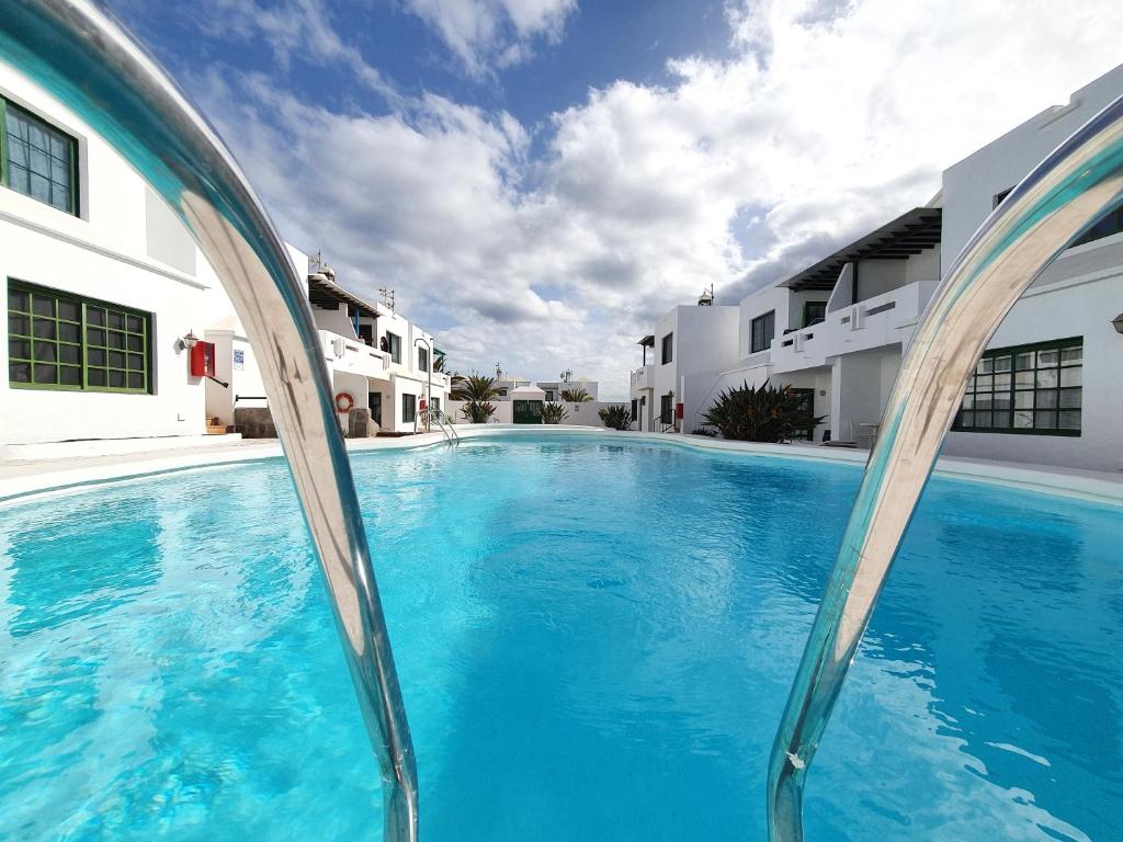 uma grande piscina azul em frente a alguns edifícios em Princesa 202 em Puerto del Carmen