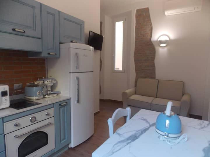 a small kitchen with a white refrigerator and a table at Via d'acqua Al Mulino -City Center- BO in Bologna