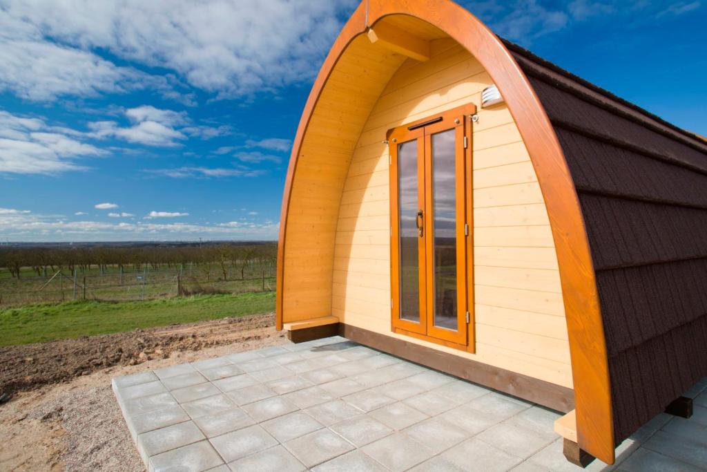 a small shed with an orange door and a patio at Ferien im Naturwagen Pod 3 in Kröpelin