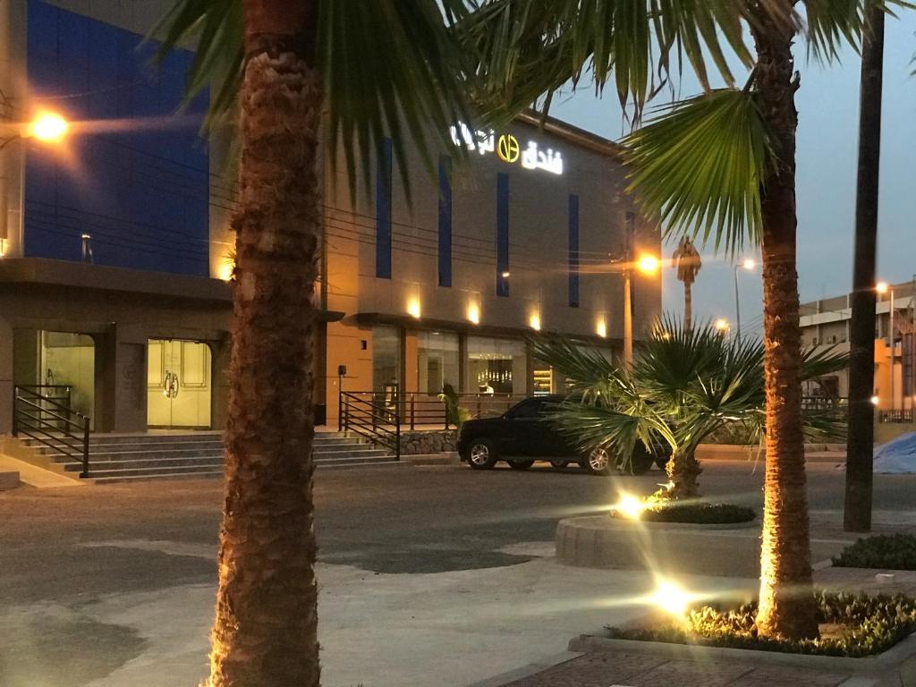 a building with palm trees in front of a parking lot at Najran Hotel in Najran