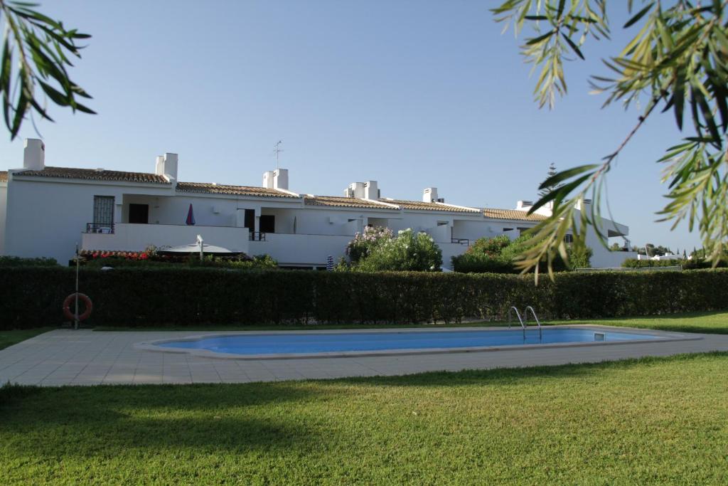 a house in the background with a pool in the grass at Apart. Barracuda in Vilamoura