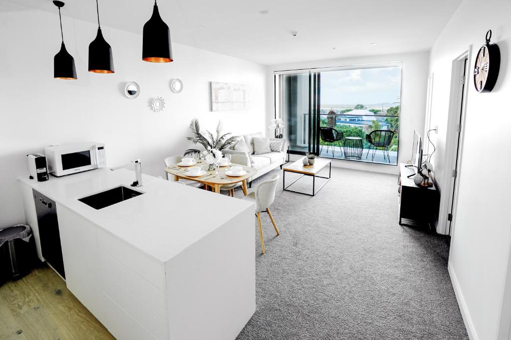Il comprend une cuisine et un salon avec un comptoir blanc. dans l'établissement CHELSEABAY Modern Apartments, à Auckland