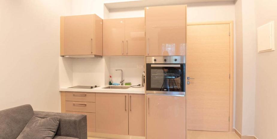 a kitchen with wooden cabinets and a stainless steel refrigerator at On the sand 1 in Palaiochóra