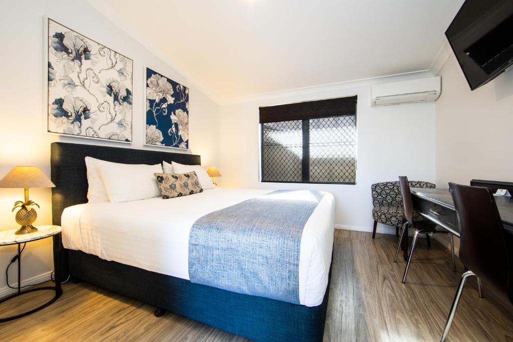 1 dormitorio con cama, escritorio y piano en New England Motor Lodge, en Glen Innes