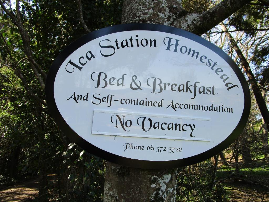 a sign for a bed and breakfast on a tree at India House & Ica Whare in Whareama, Nr Riversdale Beach in Whareama