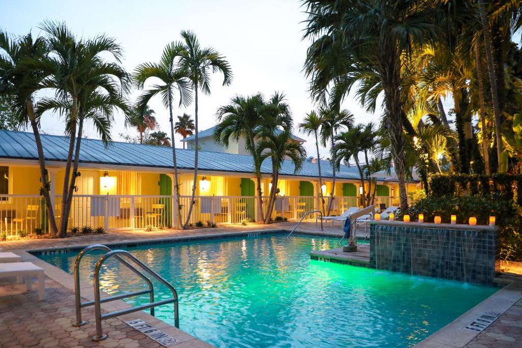 a swimming pool with palm trees and a building at Almond Tree Inn - Adults Only in Key West