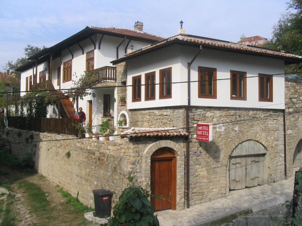 a large white house with a stone building at Hostel Mostel in Veliko Tŭrnovo