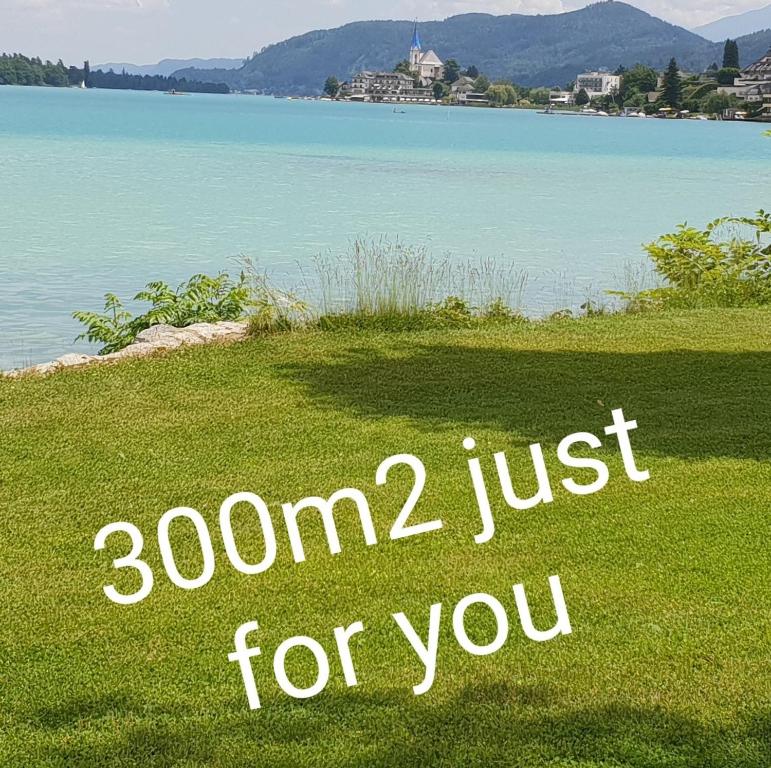 a sign on the grass next to a body of water at Cosy Lake cottage, 300m2 lake area just for you ! in Maria Wörth