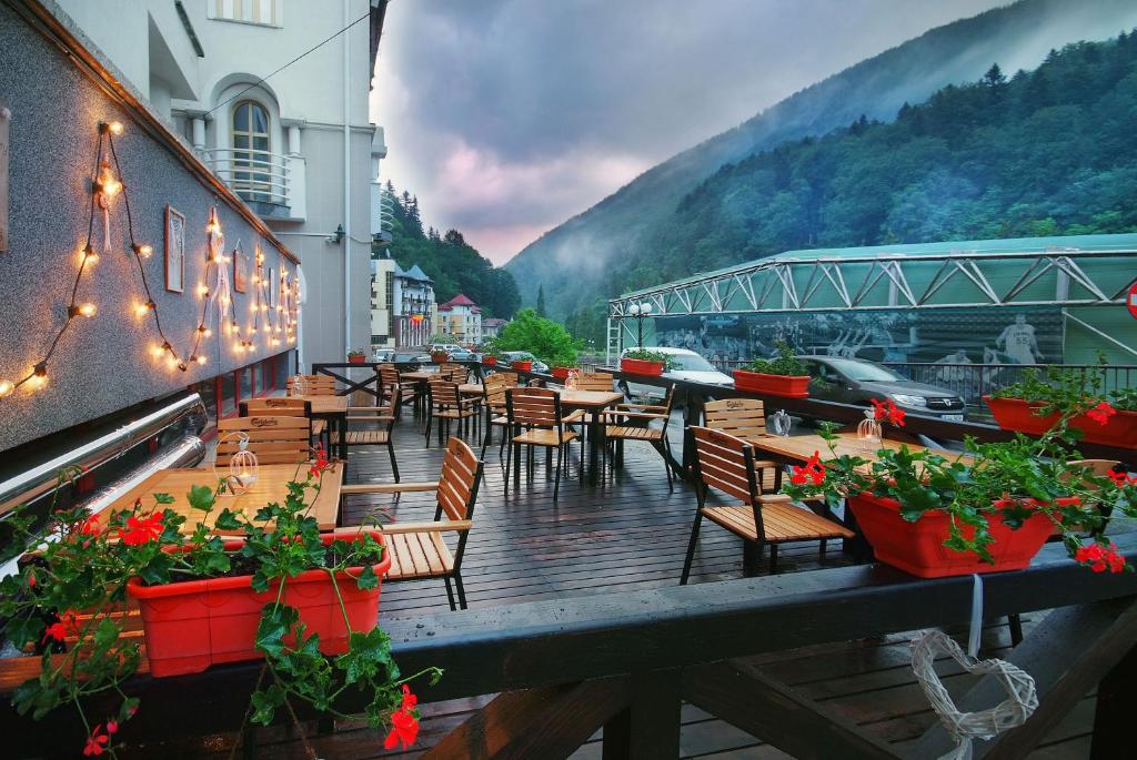 ein Restaurant mit Tischen, Stühlen und Blumen auf einem Balkon in der Unterkunft Vila Teleconstructia in Slănic-Moldova