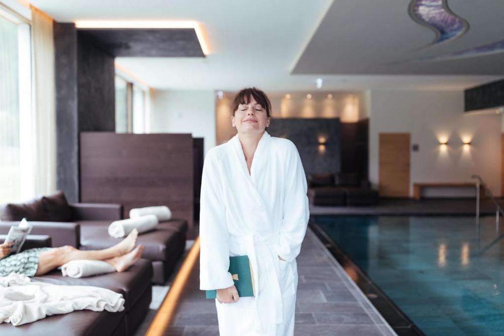 a woman in a bathrobe standing next to a swimming pool at Hotel Truyenhof in Ried im Oberinntal