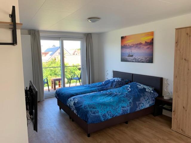 Un dormitorio con una cama y una ventana grande en de Pastorie, en Hollum
