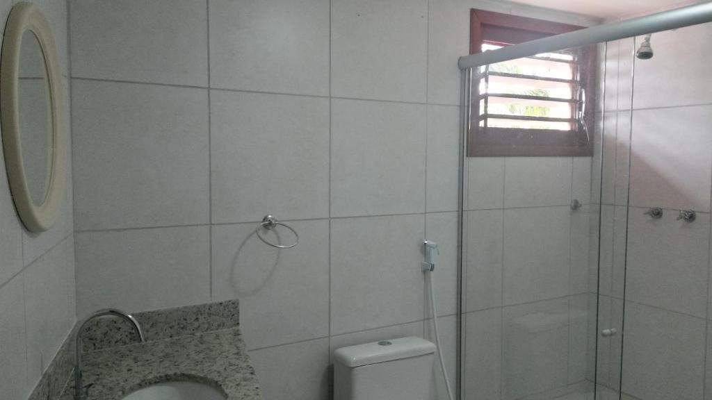 a white bathroom with a shower and a toilet at Muriú Beach Flat in Muriú