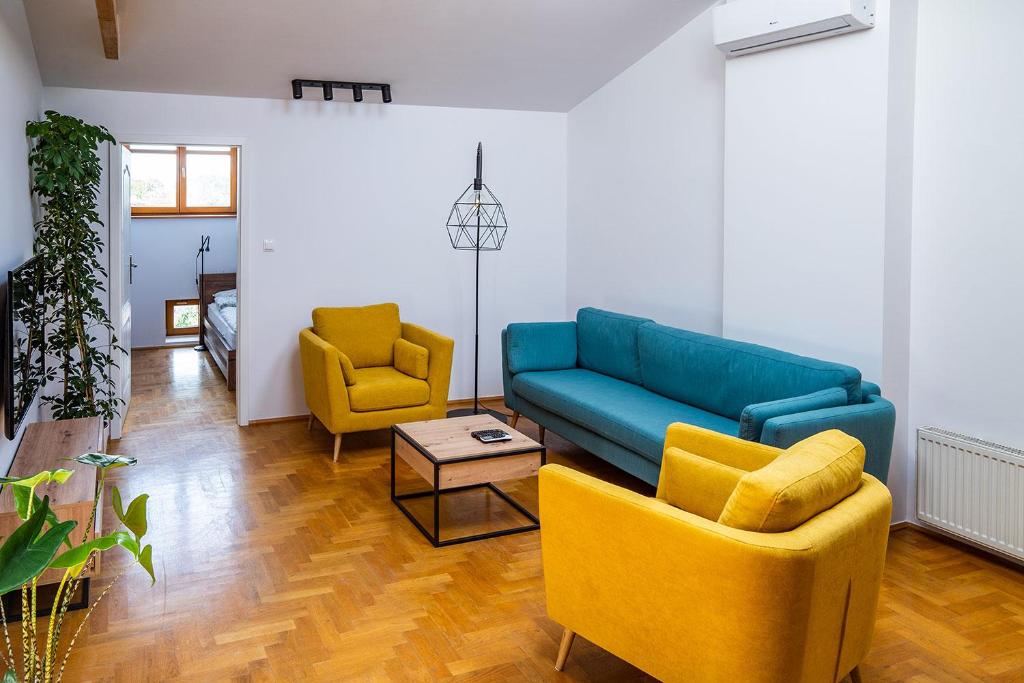 een woonkamer met een blauwe bank en 2 gele stoelen bij WONDER CRACOW in Krakau