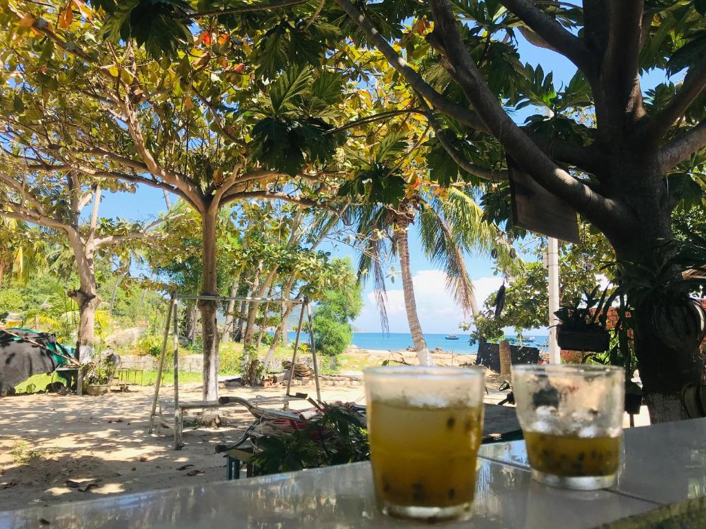 two drinks sitting on a table in front of the beach at Nhi Lo Home Stay in Tân Hiệp