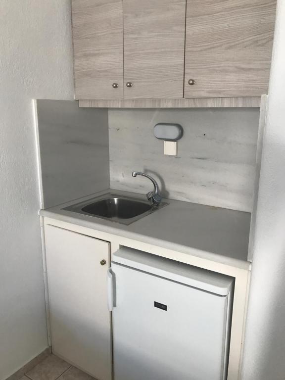 a small kitchen with a sink and wooden cabinets at Romantika in Platis Gialos