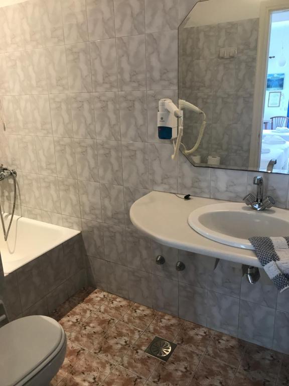 a bathroom with a sink and a toilet and a mirror at Romantika in Platis Gialos