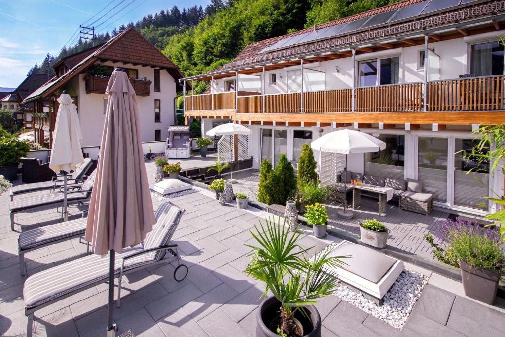 eine Terrasse mit einem Sonnenschirm und Stühlen sowie ein Gebäude in der Unterkunft Wellness Pension am Rain in Winden im Elztal