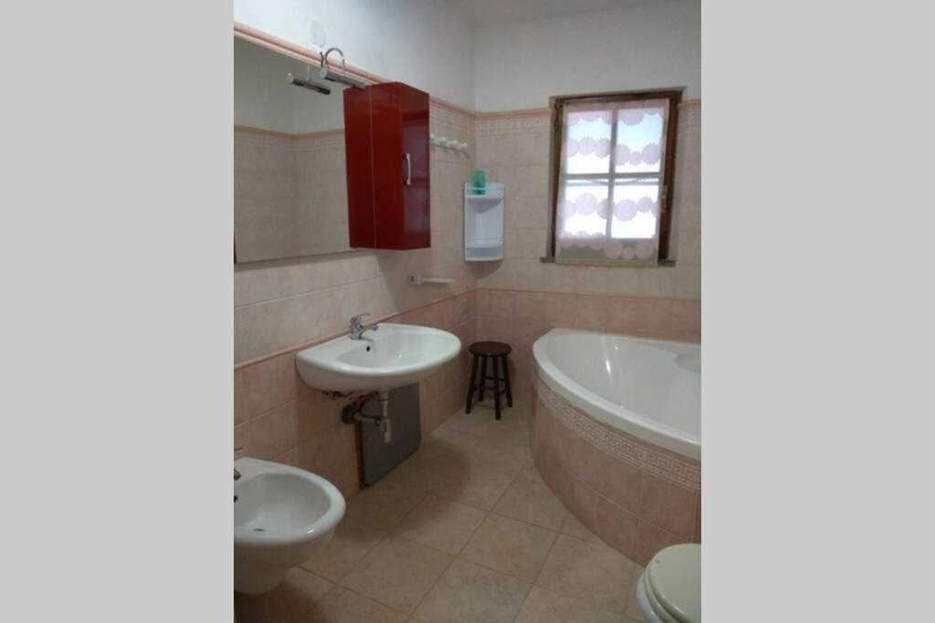 La salle de bains est pourvue d'une baignoire, de toilettes et d'un lavabo. dans l'établissement Casa vacanza Ligustro appartamento il toro, à SantʼAntìoco