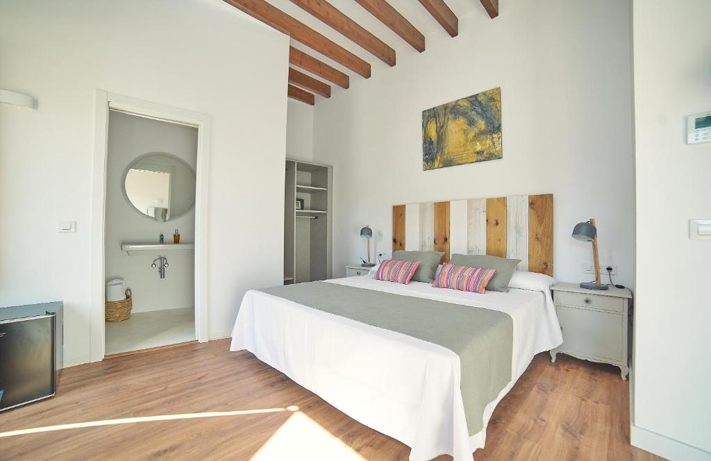 a white bedroom with a bed and a tv at Vila Alaró TI in Alaró