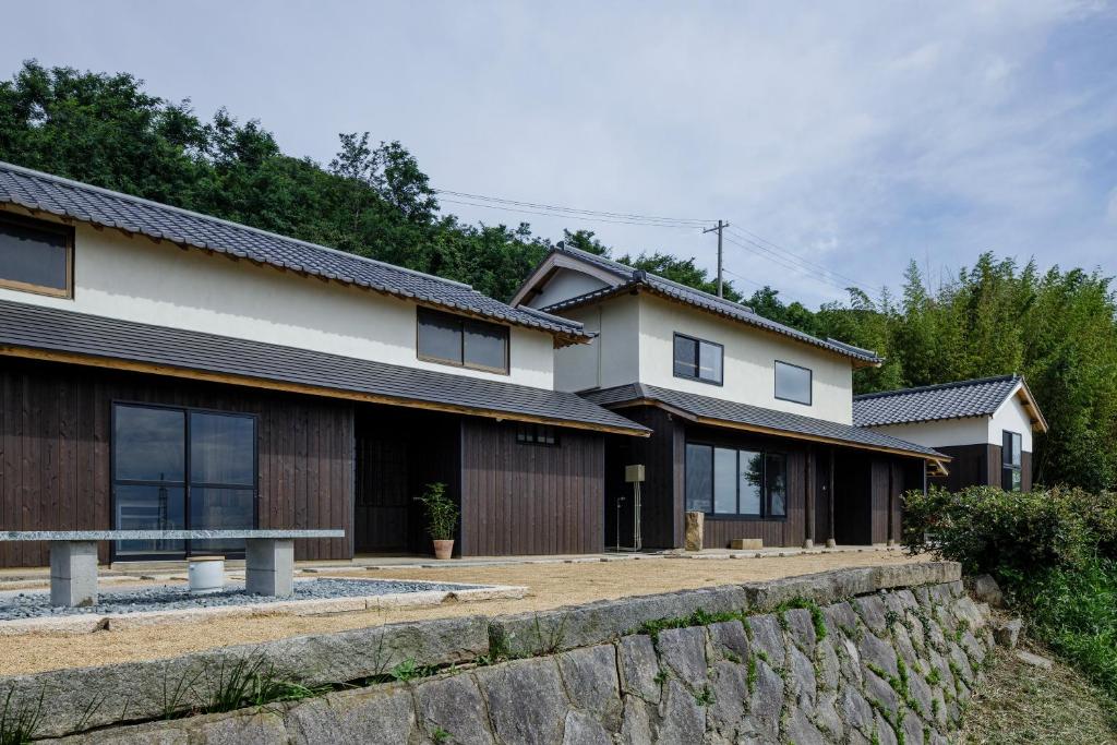 a house with a stone retaining wall next to a house at kotobukian 寿庵 in Awaji