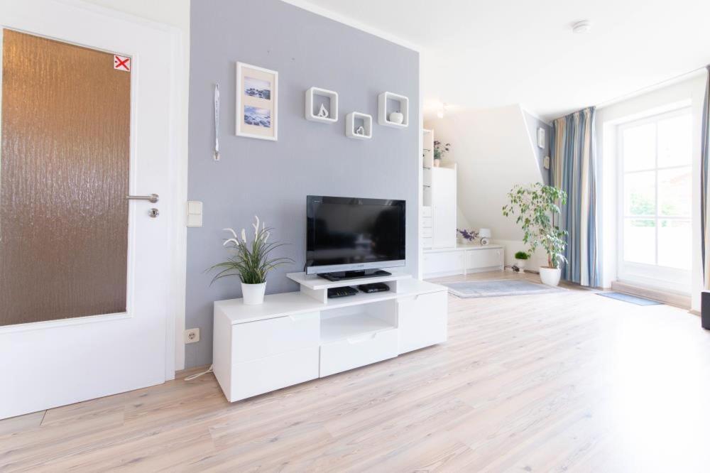 a white living room with a flat screen tv at Ferienwohnung Ocean Drive 2 in Niendorf