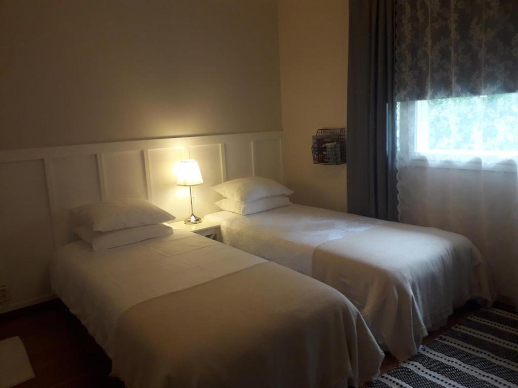two beds in a hotel room with a window at Minnan majoitus in Liminka