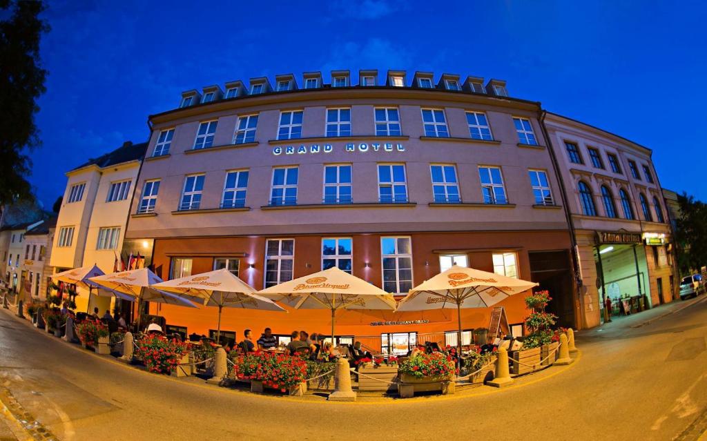 a building with tables and umbrellas in front of it at Grand Hotel Trenčin in Trenčín