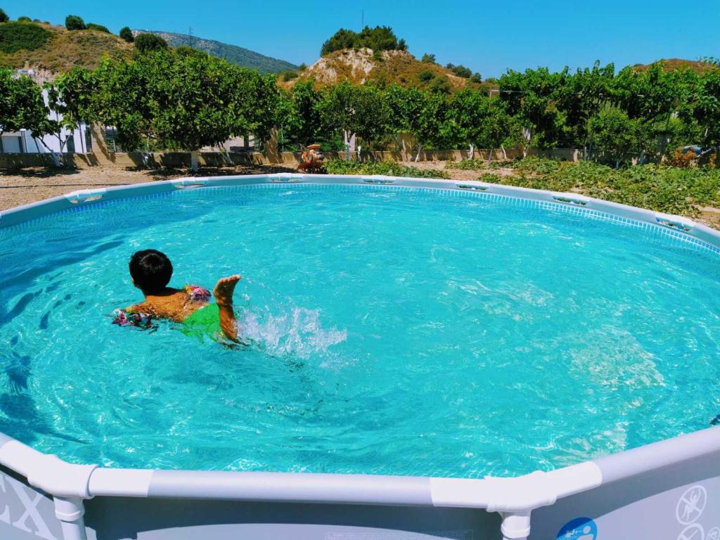 un garçon nageant dans une grande piscine dans l'établissement Garden house, à Kremasti