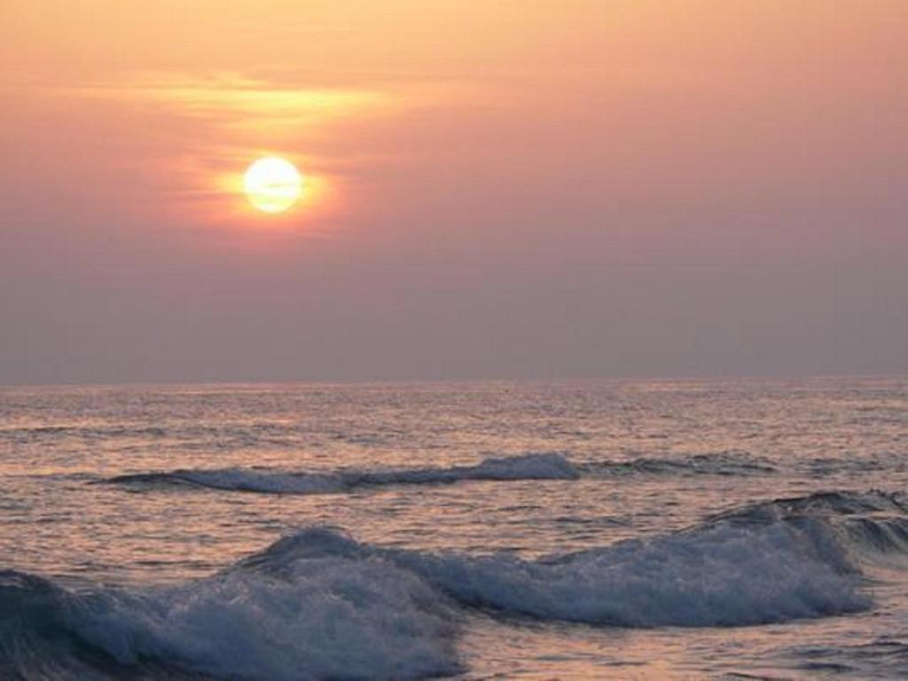 una puesta de sol sobre el océano con dos pequeñas olas en Angelica, en Perivólion
