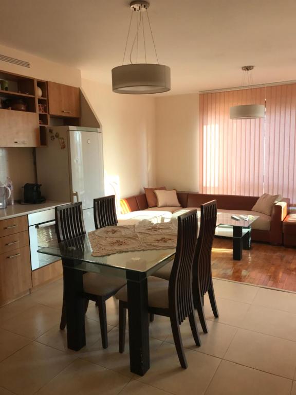 a dining room table with chairs and a living room at Apartament Sunny, Варна- център in Varna City