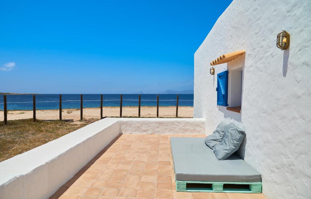a white building with a bench next to the beach at Casita Del Puerto Formentera Passport in La Savina