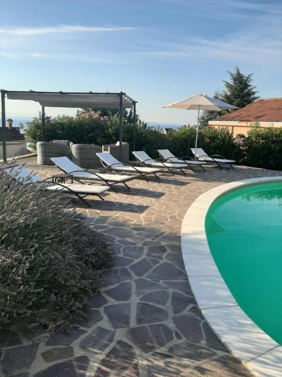 a row of lounge chairs and a swimming pool at B&B Eva in Ičići