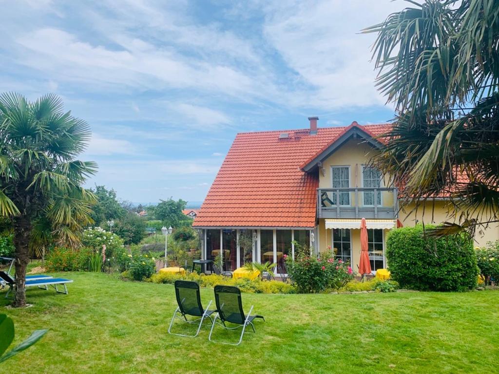 a house with two chairs in the yard at Gästehaus Helbighof in Neustadt an der Weinstraße