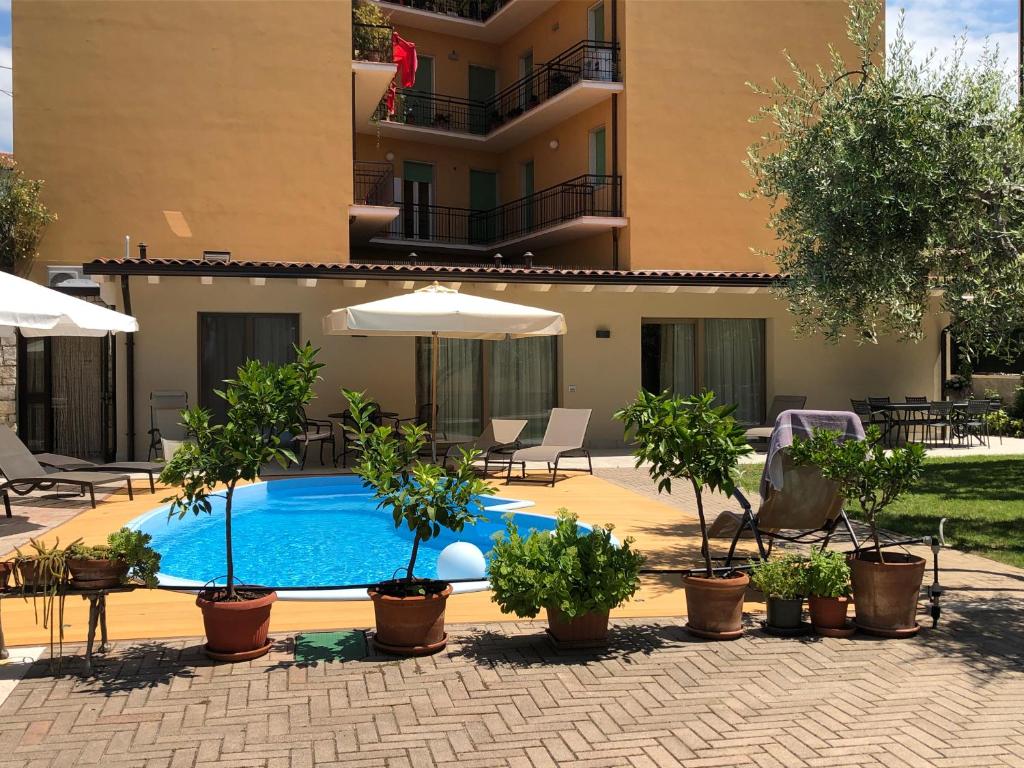 a swimming pool with plants and umbrellas in front of a building at Appartamenti Villa Dall'Agnola in Garda