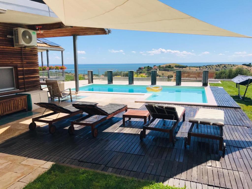 un patio con tavolo, sedie e piscina di Villa Borsacchio a Roseto degli Abruzzi