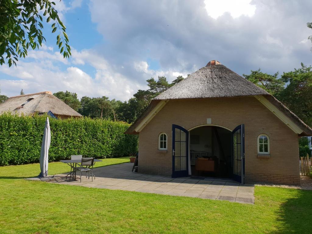 una piccola capanna con tetto di paglia e patio. di Vakantiebungalow Otterlo a Otterlo