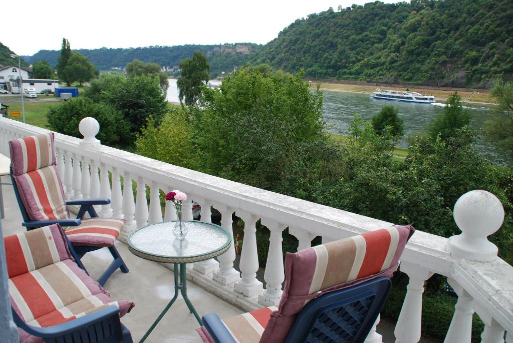 balcón con sillas y mesa con vistas al río en Paradiesisch Wohnen - Loreley, en Sankt Goarshausen