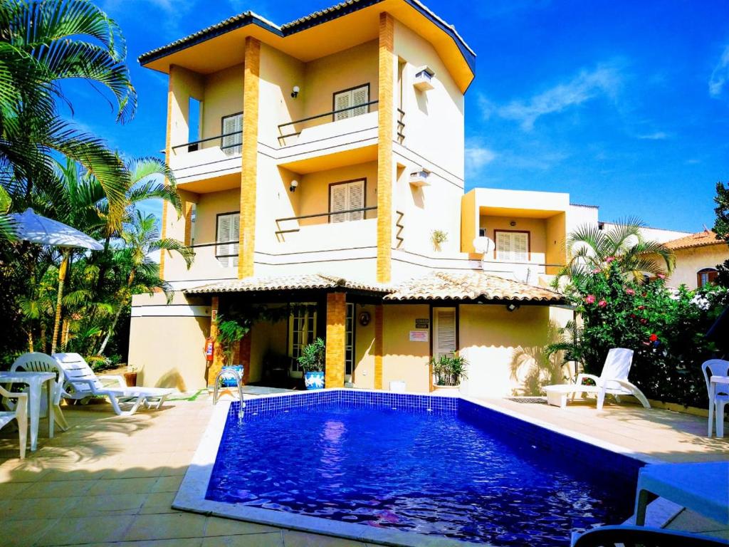 Villa con piscina frente a un edificio en Pousada Genesis, en Arraial do Cabo