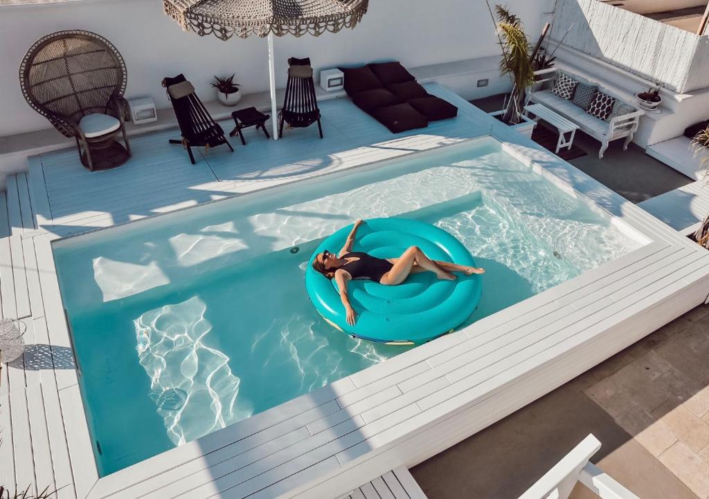 a woman floating on a raft in a swimming pool at Playa del Mar - Adults Only in Monopoli
