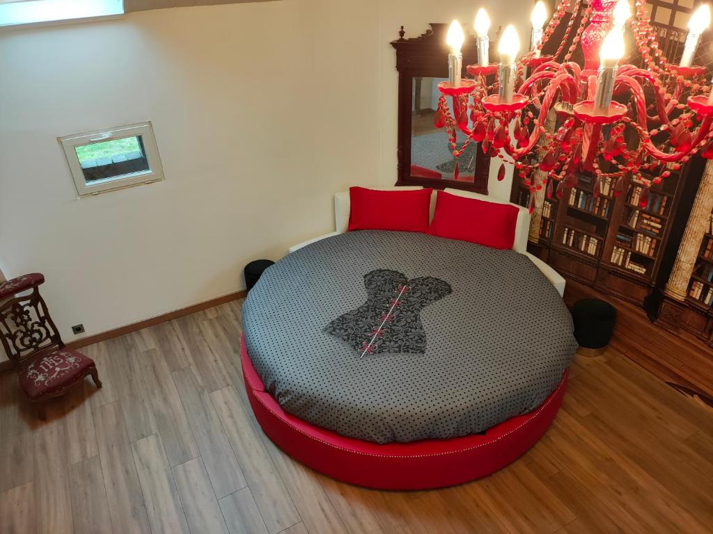 - un lit rond dans un salon avec des oreillers rouges dans l'établissement Domaine de cyrcé, à La Celle