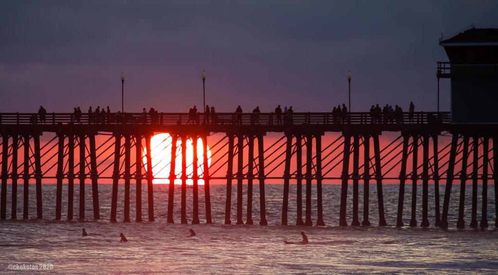 a pier with people in the water at sunset at Kaza Kokos in Oceanside